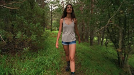 looking back at a tall beautiful brunette woman on a hike through a thick green forest in barcelonnette, france