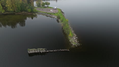 Luftaufnahme-Eines-Weißen-Lieferwagens,-Der-Am-Seeufer-Mit-Ruhigem-Schwarzen-Wasser-In-Schweden-Geparkt-Ist