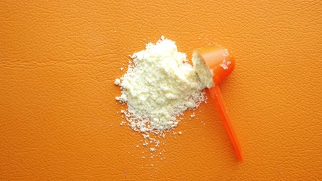 close up of baby milk powder and spoon on orange background