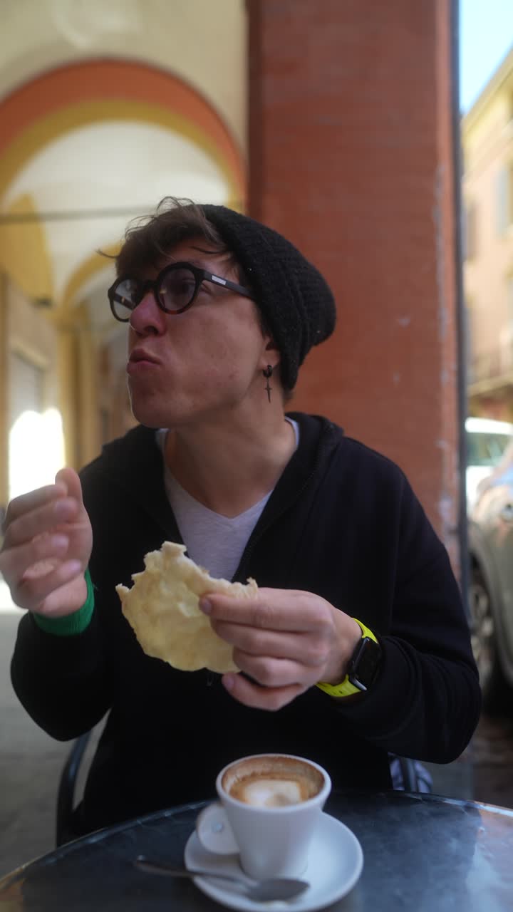Person eating bread and drinking coffee outdoors in a European city