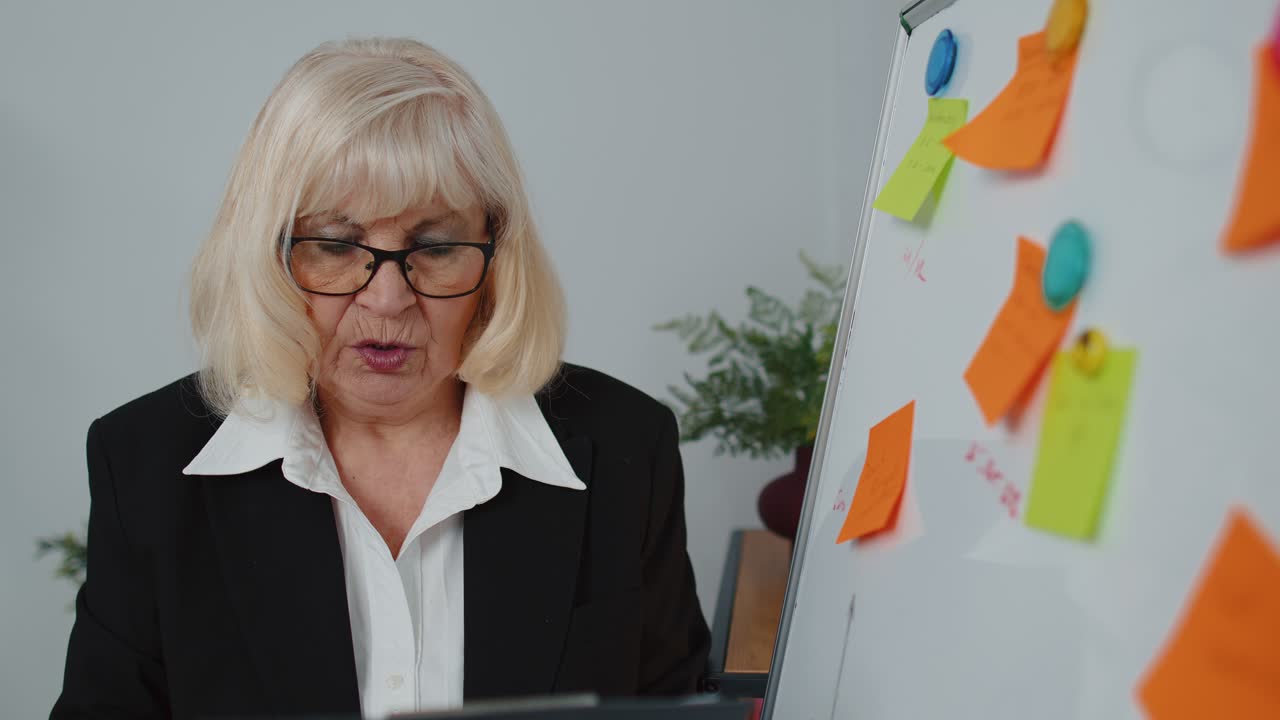 anziana vecchia donna d'affari allenatore conferenza oratore analisi infografiche disegnare sulla lavagna dell'ufficio