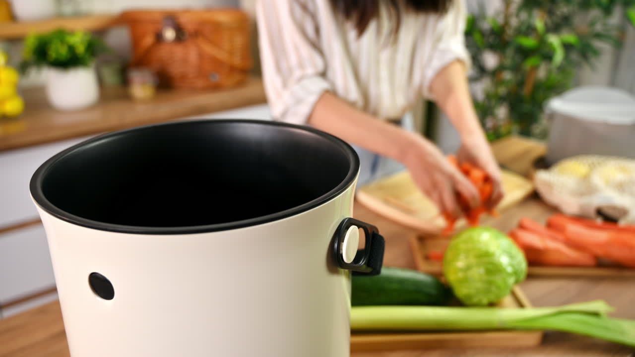 Young woman recycling vegetables peels in a compost bin. Housewife cooking food and composting organic waste in a bokashi container at home. Ecological and sustainability concept