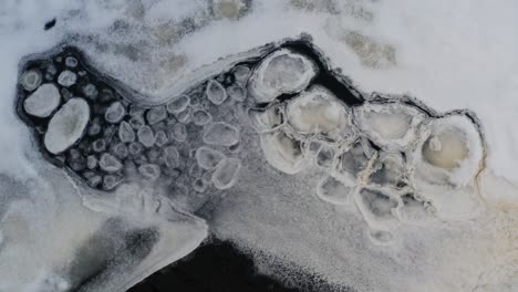 aerial view of ice shape formations float near frozen lake ice sheet