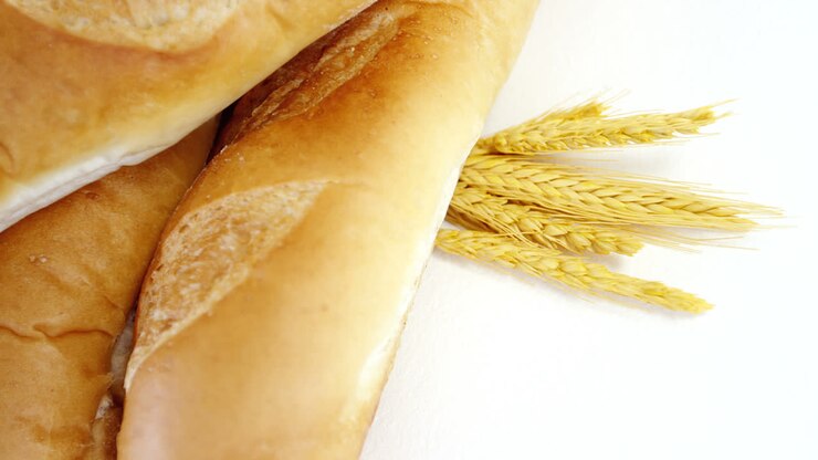 Baguettes with wheat on white background