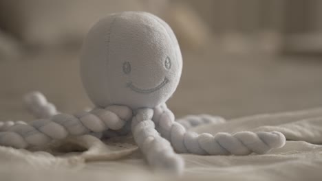 soft plush octopus toy with rope tentacles resting on cozy bedding