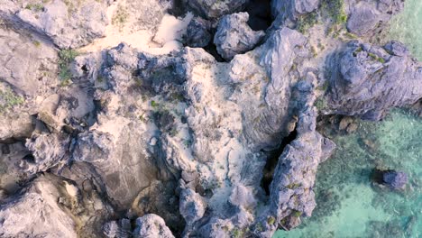 Vogelperspektive-Auf-Scharfe,-Spitze-Felsen-Im-Türkisfarbenen-Wasser-Auf-Einer-Tropischen-Insel