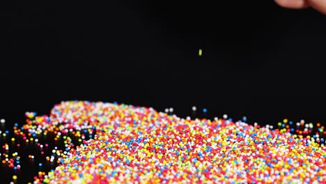 hands interacting with vibrant, tiny candy sprinkles