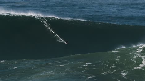 Slow-motion-of-a-big-wave-surfer-riding-a-crazy-monster-wave-in-Nazaré,-Portugal