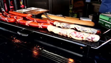 Slow-motion-panning-shot-of-hot-dogs-being-cooked-at-a-street-vendor-in-London