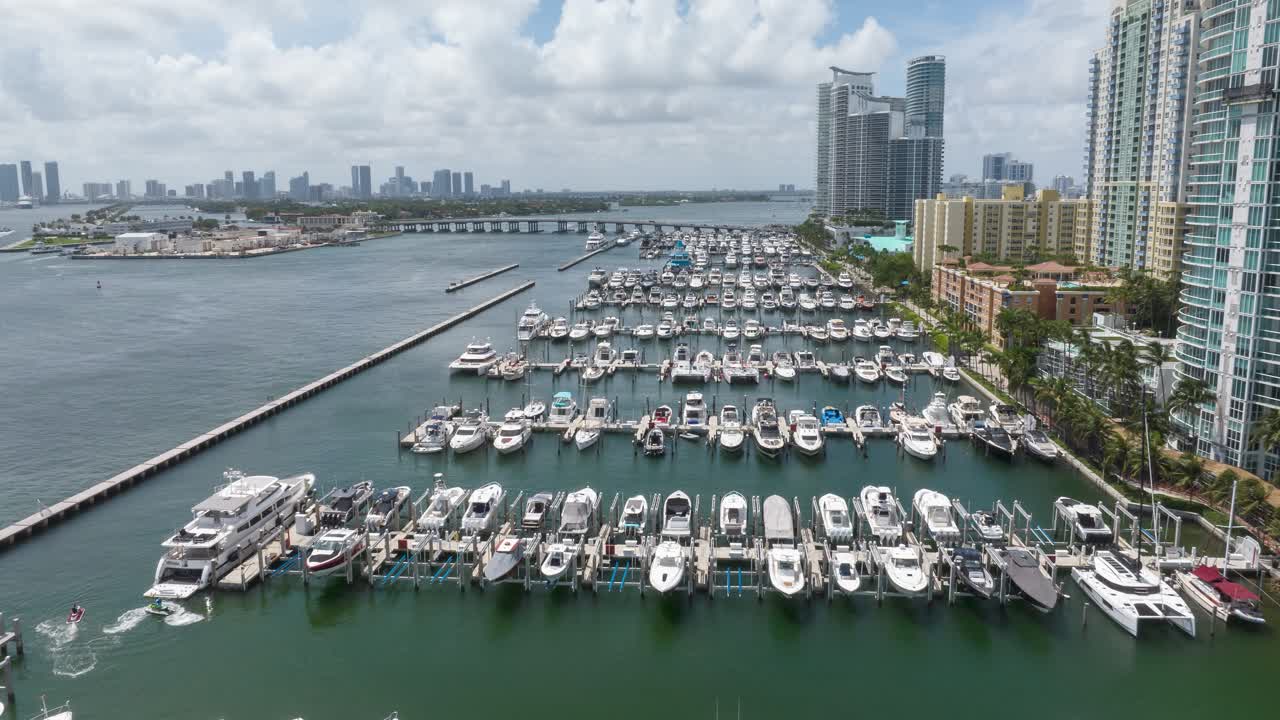 hyperlapse aéreo de la marina de miami beach que muestra yates de lujo y impresionantes vistas a la orilla con el horizonte de la ciudad y la calzada de macarthur en el fondo