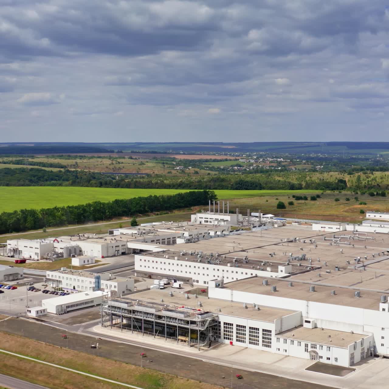 Factory on nature background. Modern large industrial complex on field in summer. Manufacture among green landscape. Aerial view