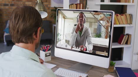 hombre de negocios caucásico sentado en un escritorio usando una computadora haciendo una videollamada con un colega masculino