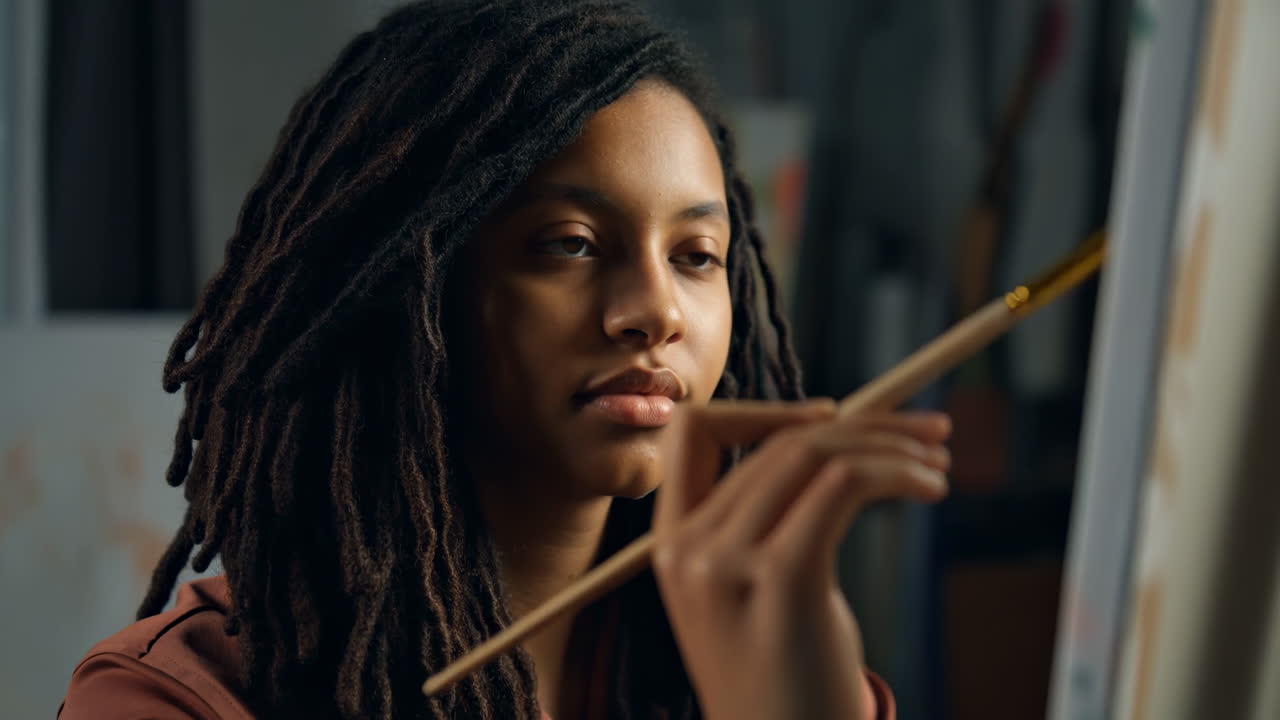 Portrait of a woman artist with dreadlocks painting