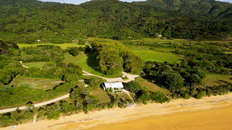 Aerial-over-the-DOC,-Department-of-Conservation,-office-building-at-Totaranui-Beach-in-the-Abel-Tasman-National-Park,-South-Island,-New-Zealand