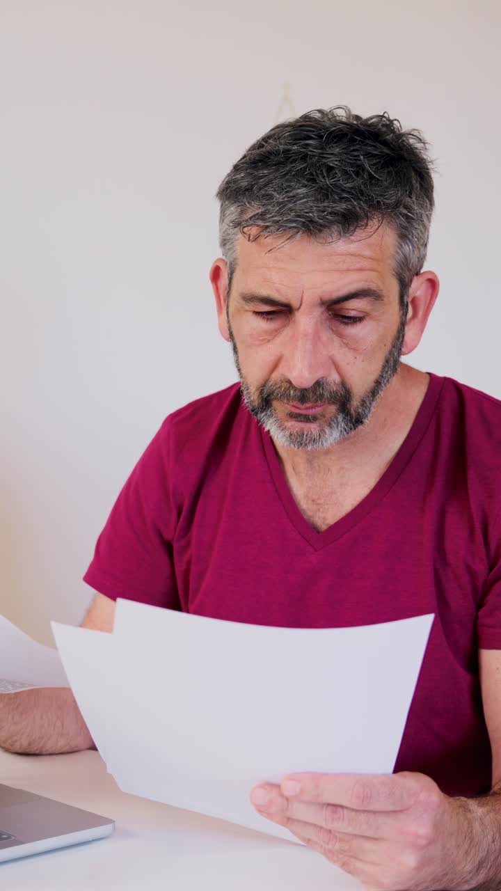 Hombre estresado leyendo documentos y frotándose los ojos