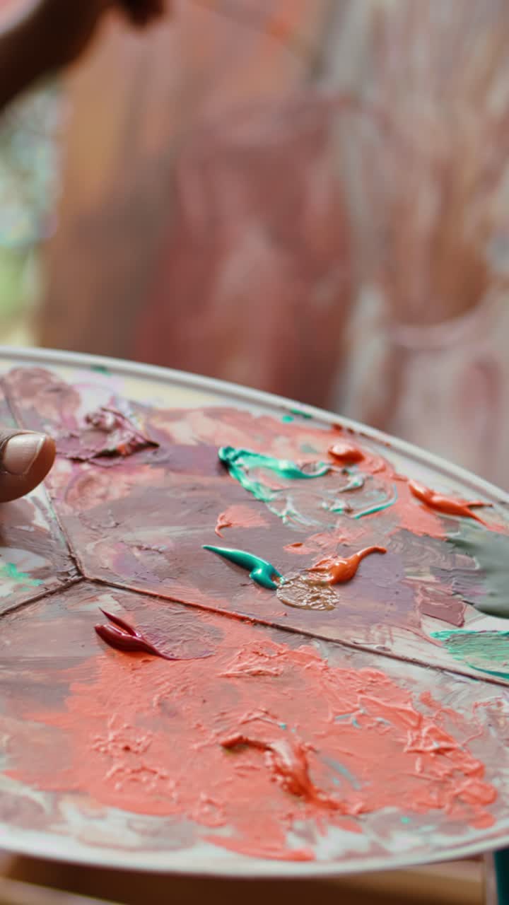 Artist's Hand Holding a Paint Palette with Vibrant Colors