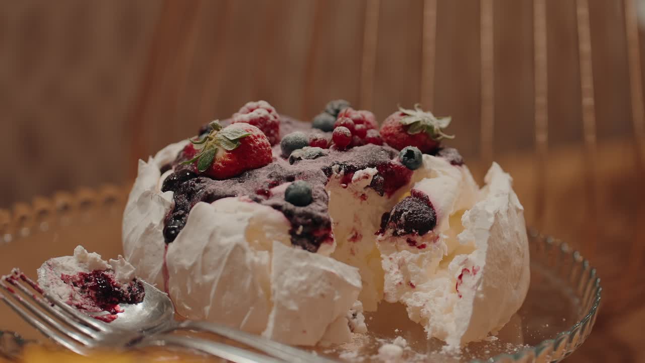 pavlova topped with mixed berries sliced and served on elegant glass plate