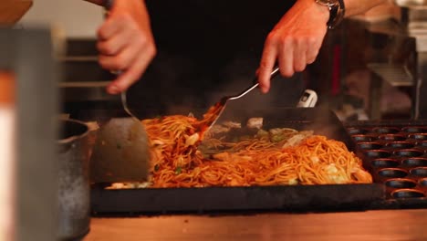 chef haciendo fideos tradicionales japoneses con tocino y verduras.