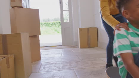 girl pushing brother on skateboard in between boxes on moving in day