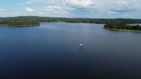 high aerial shows long wake behind small boat motoring on blue lake