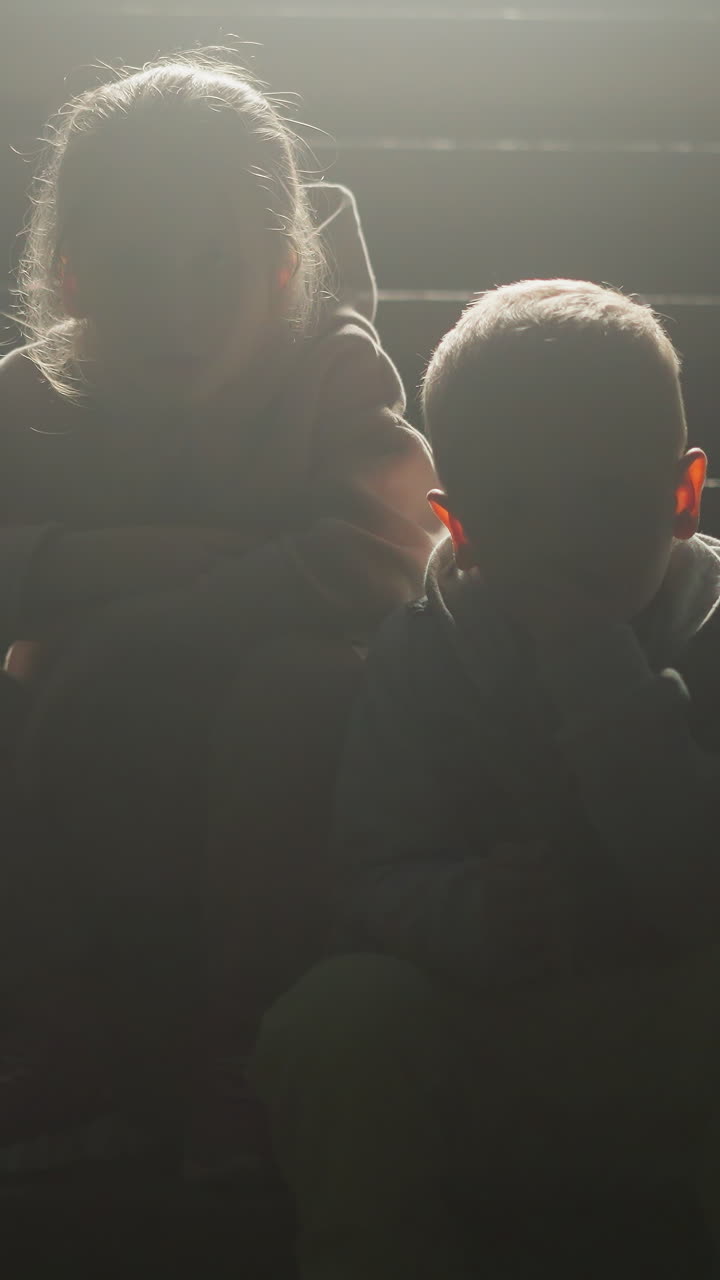 niños siluetas en las escaleras de la cabaña por la noche. niño pequeño y niña descansan sentados en los escalones de la casa de campo. niños tranquilos pasan tiempo juntos por la noche