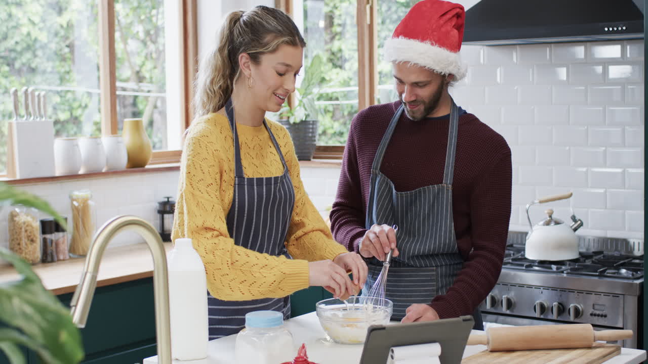 una pareja feliz horneando galletas de navidad en la cocina de casa, en cámara lenta.