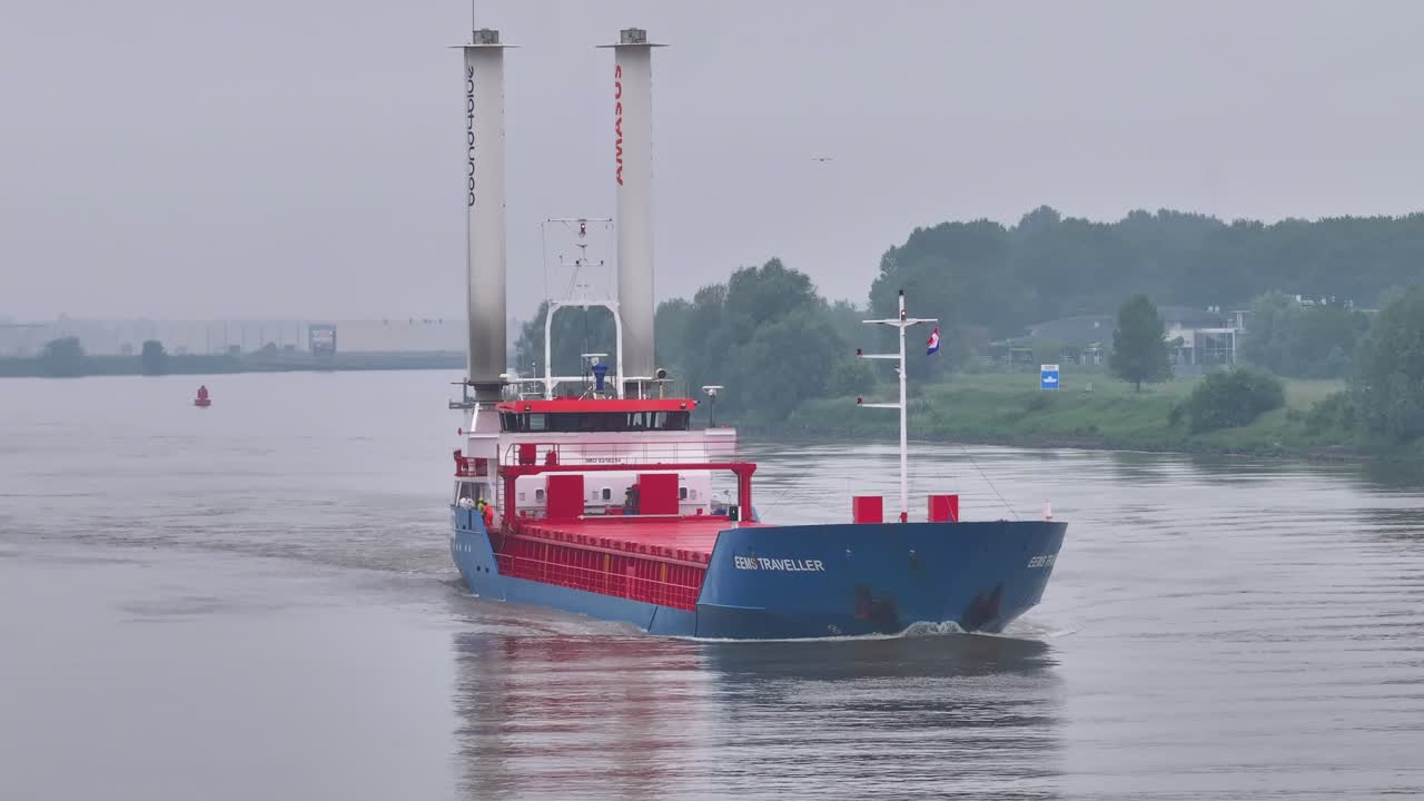 The "EEMS TRAVELLER" Cargo Ship with Rotor Sails Navigating a Waterway