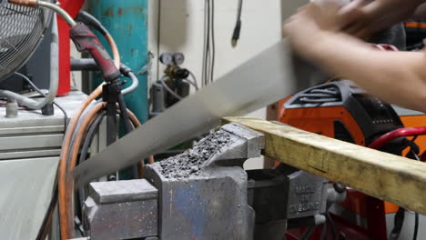 Worker-Cutting-Wood-With-A-Handsaw,-Industrial-Workshop