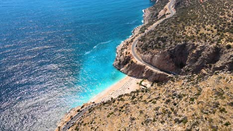 Volar-Un-Dron-A-Lo-Largo-De-La-Franja-Costera-De-Una-Montaña-Verde-Sobre-Una-Carretera-De-Montaña,-Conducir-Camiones-A-La-Playa-Y-La-Costa-Mediterránea