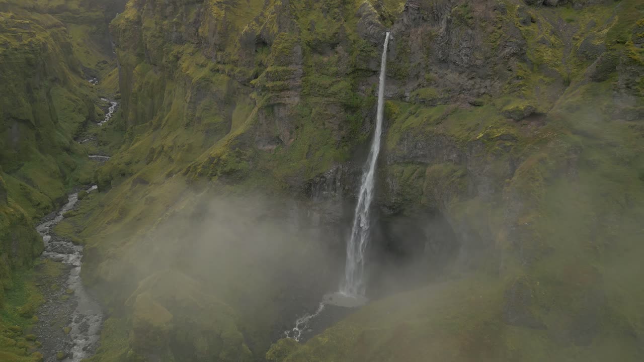 volando a través de las nubes para revelar una gran cascada majestuosa en la distancia