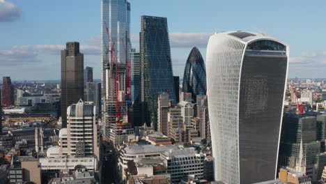 Modern-futuristic-buildings-made-from-glass-and-steel-in-business-district.-Skyscrapers-in-City-lit-from-side.-Tower-cranes-on-construction-site-of-new-building.-London,-UK