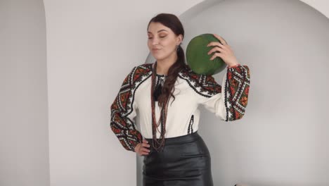 encantadora mujer joven en bordado auténtico traje ucraniano sostiene un gran pedazo de queso cabeza y sonríe