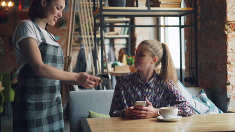 woman paying with phone at cafe