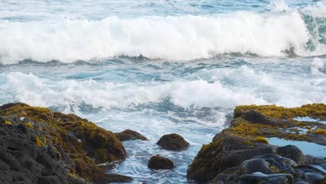 las olas chocan contra las rocas cubiertas de musgo