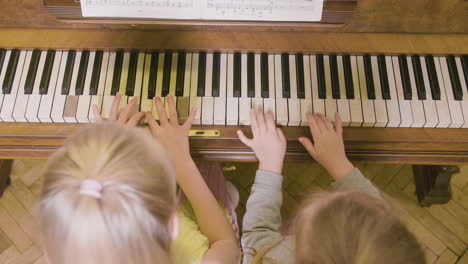 vista superior de dos niñas tocando el piano antiguo en casa 1