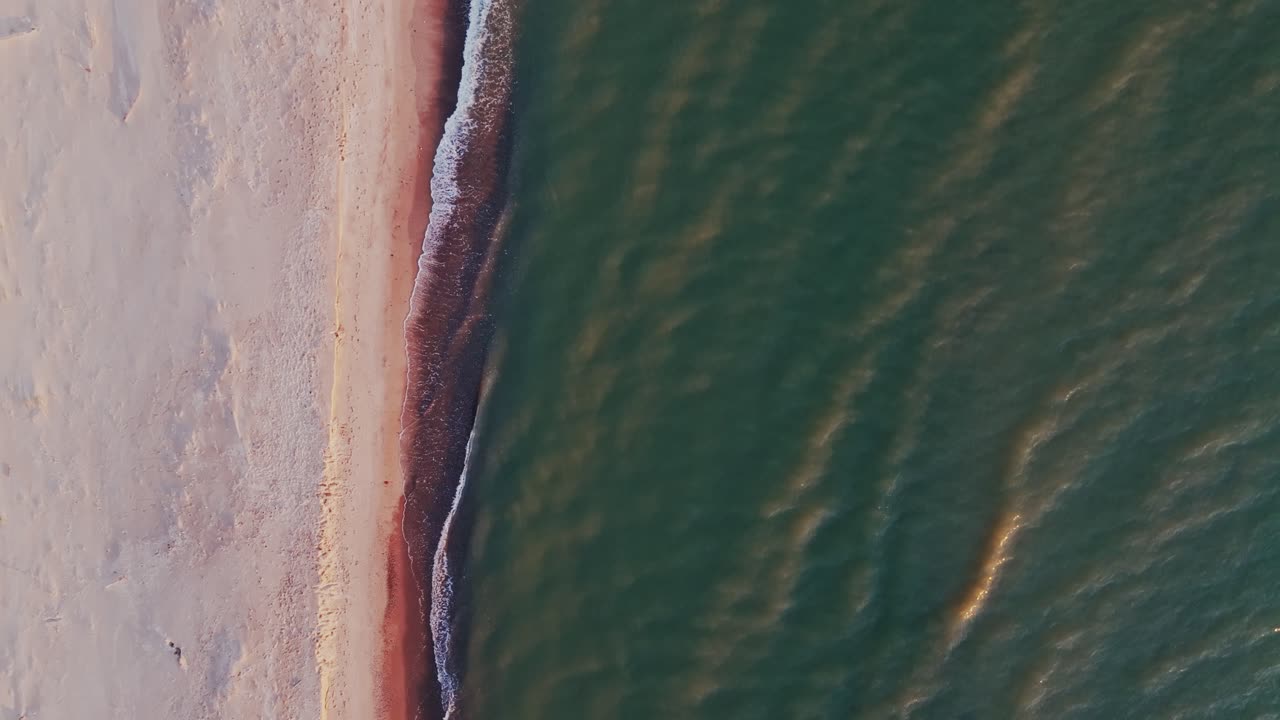 Warm golden hues reflect on gentle Baltic waves along Ziemupe coast at dusk