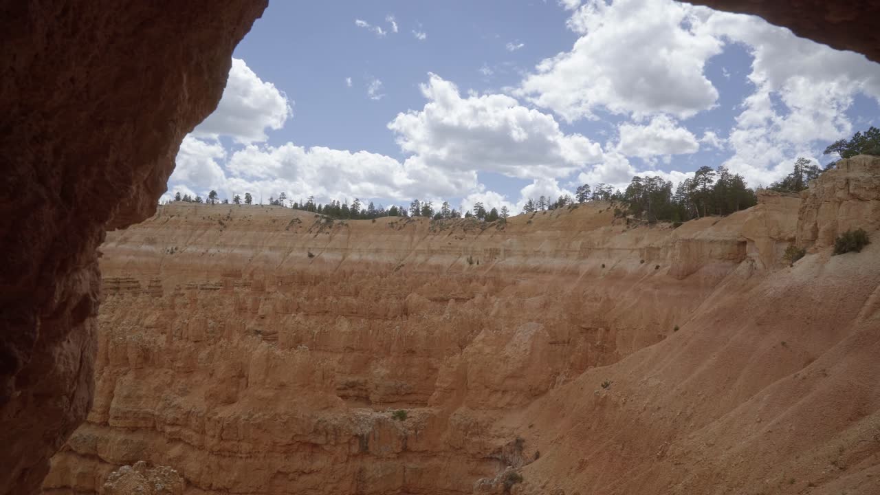 tiro de mano desde una pequeña cala de roca mirando hacia un acantilado de formaciones de piedra arenisca hoodoo naranja en el desierto del sur de utah en un día de verano cálido y nublado