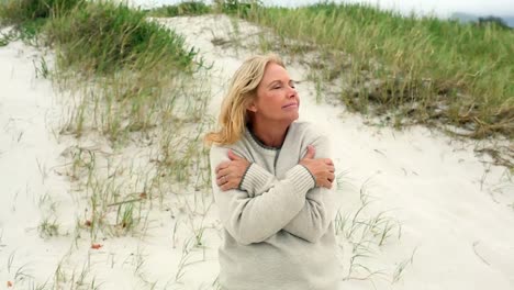 smiling retired woman shivering on the beach