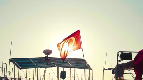 turkish flag waving over ships in the harbor of bodrum, turkey
