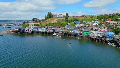 drone shot of boats at the palafitos stilt houses, sunny day in castro city, chile