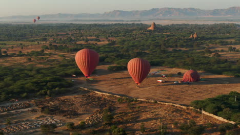 Aerial-view-of-hot-air-balloon-ready-for-start-with-mountain-ridge-and-river-in-background-at-sunrise---Bagan,-Myanmar