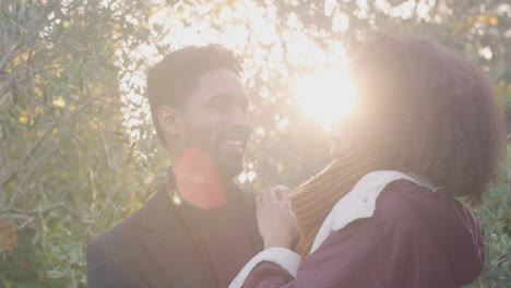 retrato de una pareja joven y amorosa abrazándose al aire libre en el campo de otoño o invierno contra el sol abrasador