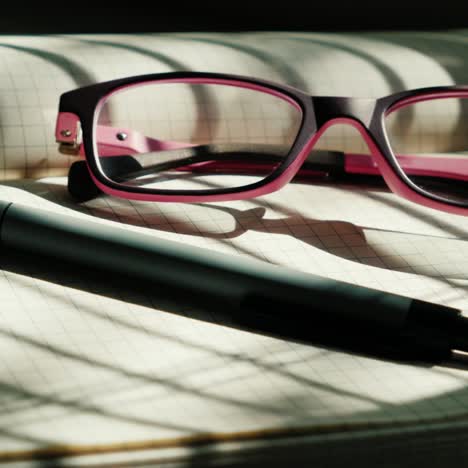 Las-Gafas-Están-En-Un-Cuaderno-Abierto-En-Una-Hoja-En-Blanco