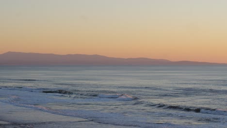 golden hour sunset over the ocean with mountains in the background horizon