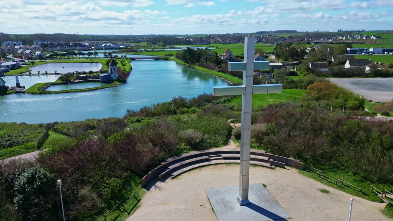 Croix de Lorraine monument with windmill in background, Courseulles-sur-Mer, Normandy, France. Aerial drone forward