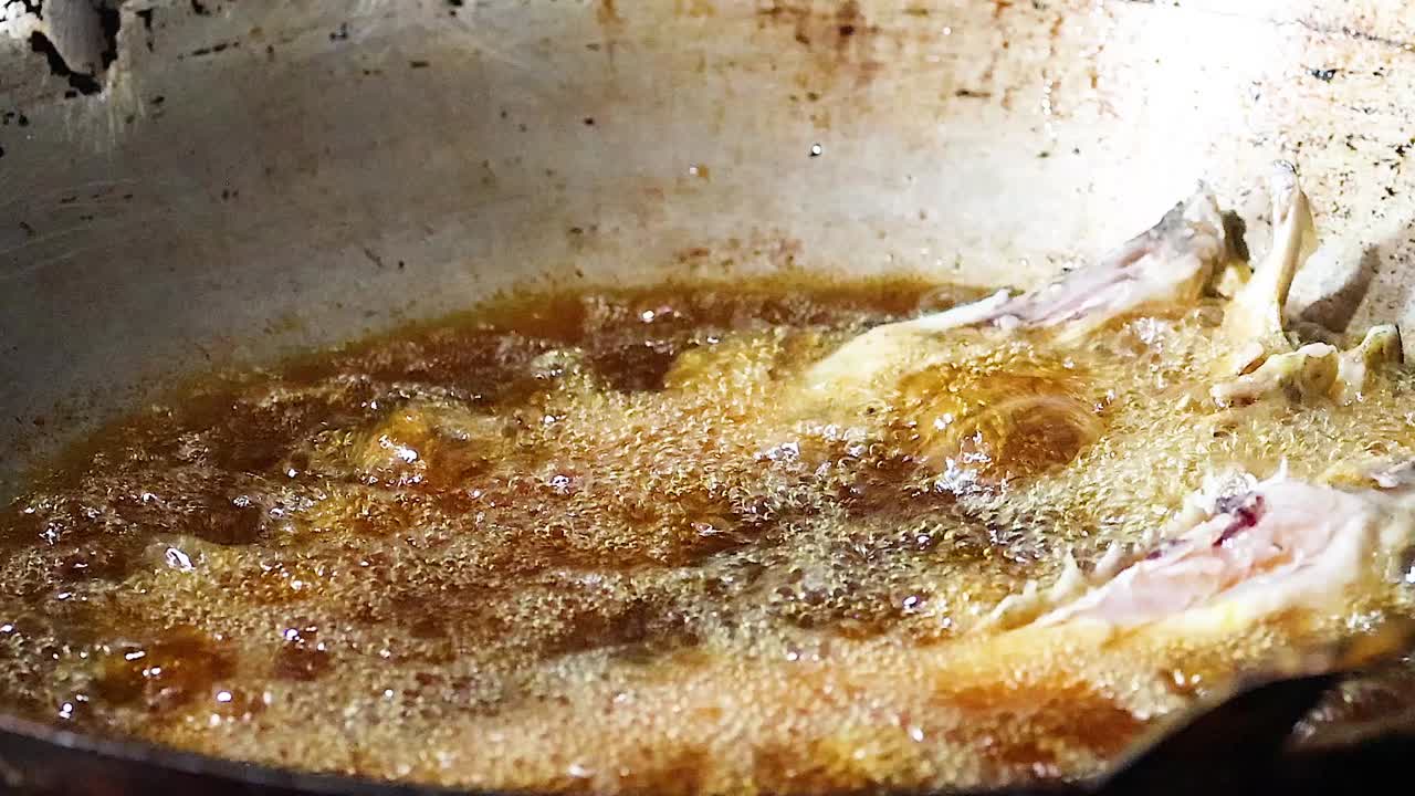Close-up of fish sizzling in hot oil, showcasing the rich golden texture and bubbling surface.