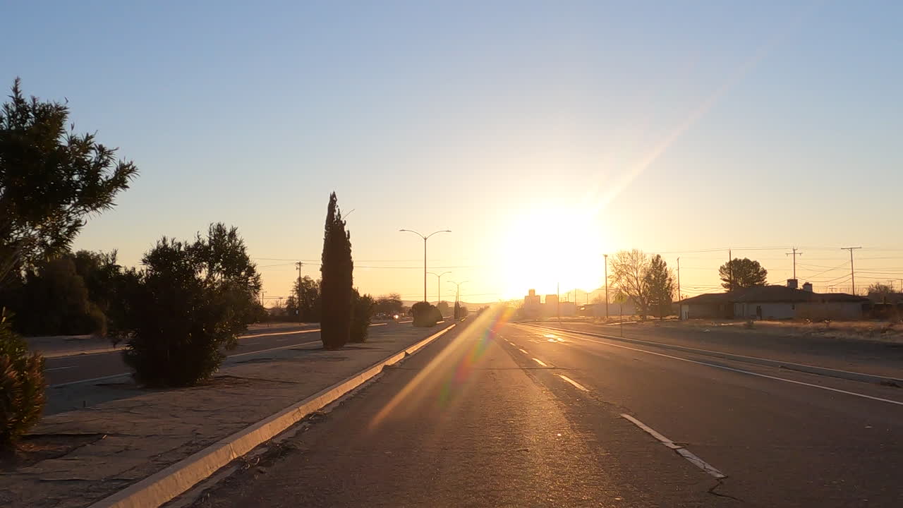 conducir a un área urbana en una autopista durante una puesta de sol dorada - punto de vista del conductor