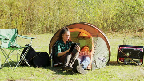 Schöne-Junge-Freundin,-Die-Ihr-Tablet-Vor-Dem-Campingzelt-Benutzt