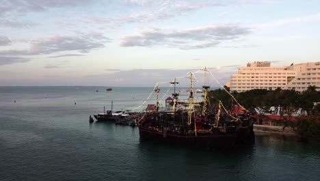 Orbit-shot-of-a-pirate-ship-at-golden-hour-with-a-building-on-the-background