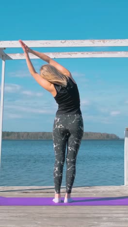 mujer practicando yoga junto al lago